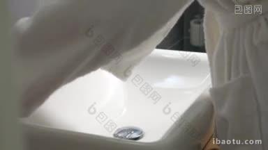 穿着白色毛巾布长袍的女人在浴室里用液体肥皂
